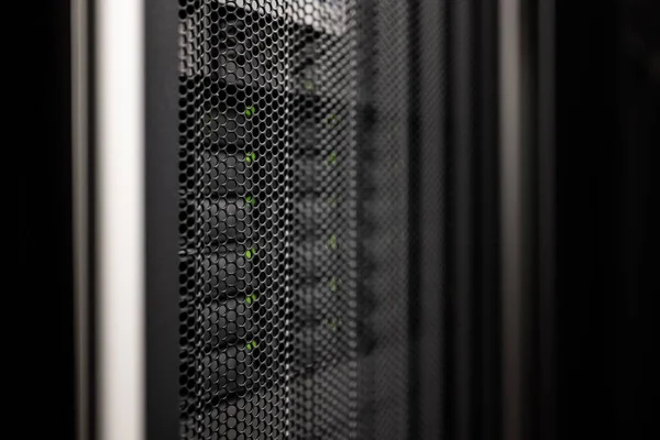 gray black server cabinet door made of perforated metal with network storage hard drives with green leds behind