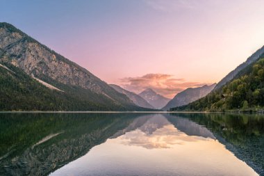 wonderful evening mood at the tyrolean lake plansee with reflection of the mountains in the clear water clipart