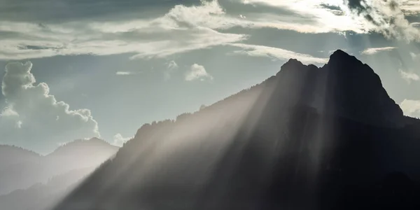 雷雨の後の日没の日没の山の紋章の上に巨大な放牧光線ビーム ロイヤリティフリーのストック画像