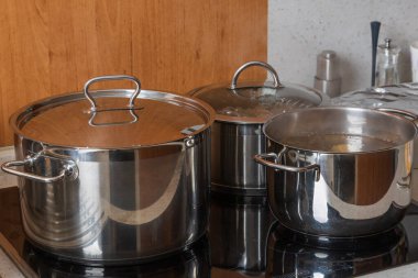 Metal silver pots on the stove in the kitchen. Glass ceramic cooking plate.