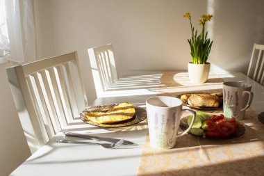 Breakfast on a fork on a white table in the morning sun in the kitchen.