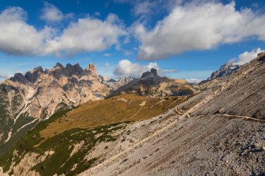 İtalyan Dolomites Tre Cime 'de manzara. Açık mavi bir gökyüzü var ve bir yerlerde bulutlar var..