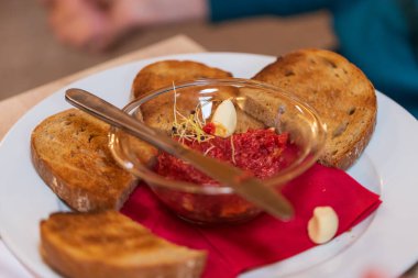 Cam kasede biftekli tartar. Etrafta kızarmış ekmek var. Sarımsaklı tost..