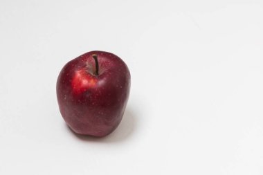 Beyaz arka planı olan beyaz bir masada koca bir kırmızı elma..