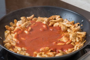 Tavada kızartmak için doğranmış tavuk. Yan yemek domates suyu..