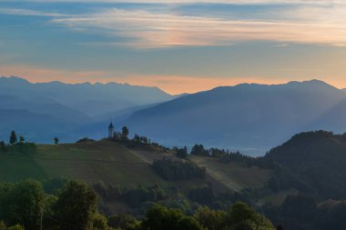 Slovenya 'nın Jamnik köyündeki Aziz Primoz Kilisesi, Avrupa. Kilise dağların yamacında. Gündoğumu, arka planda dağ zirveleri.