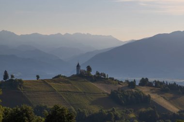 Slovenya 'nın Jamnik köyündeki Aziz Primoz Kilisesi, Avrupa. Kilise dağların yamacında. Gündoğumu, arka planda dağ zirveleri.