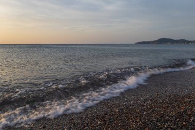 Denizin dalgaları çakıl taşı plajını yıkıyor.