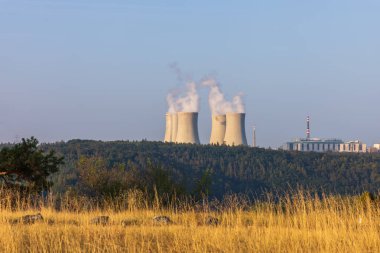 Çek Cumhuriyeti, Avrupa 'daki Dukovany nükleer enerji santrali. Duman soğutma kuleleri. Gökyüzünde bulutlar var. Ön planda İskoçya 'nın doğası var.