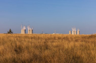 Çek Cumhuriyeti, Avrupa 'daki Dukovany nükleer enerji santrali. Duman soğutma kuleleri. Gökyüzünde bulutlar var. Ön planda İskoçya 'nın doğası var.