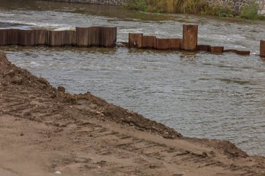 Svratka river in the city of Brno on Porici Street. Iron piles in the water. clipart