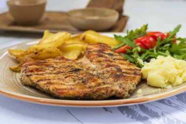 Restoranda öğle yemeği. Izgara tavuk göğsü, patates ve salata.
