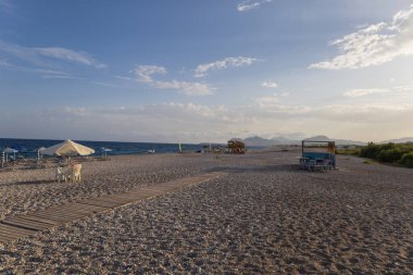 Yunanistan 'ın Rodos adasında deniz kıyısında bir sahil. Sahilde güneş yatakları ve şemsiyeler