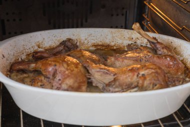 Pişirme tepsisindeki ördek. Ördek fırında pişiyor. Koyu kahverengi kümes hayvanları.