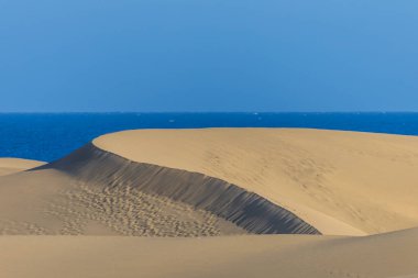 Maspaloma 'daki çöl manzarası ve kum tepeleri. Kum tepeleri ve deniz manzarası. Gran Kanarya Adası İspanya