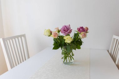 İç taraftaki bir masada vazoda renkli güller.