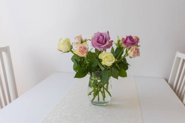 İç taraftaki bir masada vazoda renkli güller.