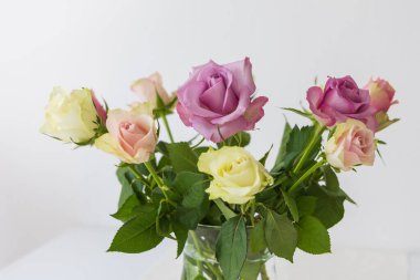 İç taraftaki bir masada vazoda renkli güller.