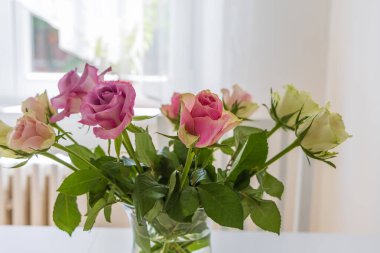 İç taraftaki bir masada vazoda renkli güller.