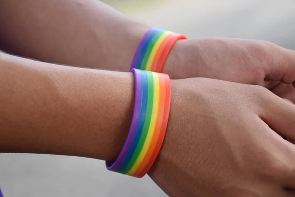 Rainbow wristband wearing in hand of young asian gay to show and represent gender diversity, to respect human rights in alternative sex, to stop punishing homosexuals in some religions.
