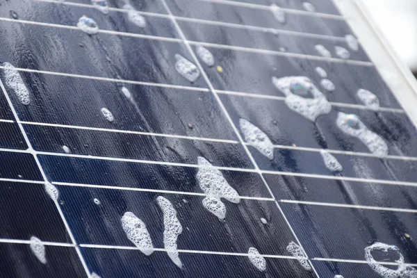 stock image Closeup photovoltaic panel which had waterdrops and sponges on the surface, soft and selective focus, concept for using natural power in daily life around the world.