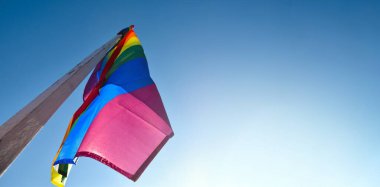 Gökkuşağı bayrağına bakın, LGBT simbol, açık mavi arka plan, yumuşak ve seçici odak, LGBT onur ayı konsepti, Haziran, dünya çapında, kopyalama alanı.