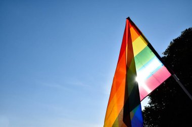 Gökkuşağı bayrağına bakın, LGBT simbol, açık mavi arka plan, yumuşak ve seçici odak, LGBT onur ayı konsepti, Haziran, dünya çapında, kopyalama alanı.