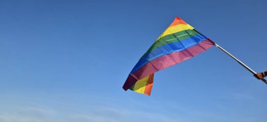 Gökkuşağı bayrağı, LGBT sembolü, açık mavi arka plan, yumuşak ve seçici odak, LGBT onur ayı konsepti, Haziran, Haziran, dünya çapında, kopyalama alanı.