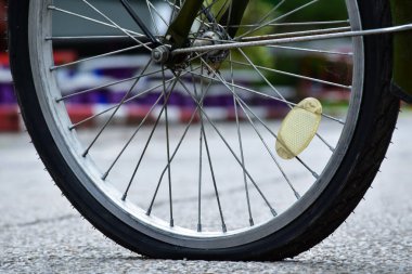 Düz ve yolun kenarındaki kaldırıma park edilmiş bir bisikletin arka tekerleği..