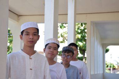 Genç Güneydoğu Asyalı çocuklar balkonun önünde sıra sıra bekliyor ve günlük aktivitelerini yapmak için bekliyor, yumuşak ve seçici bir şekilde..
