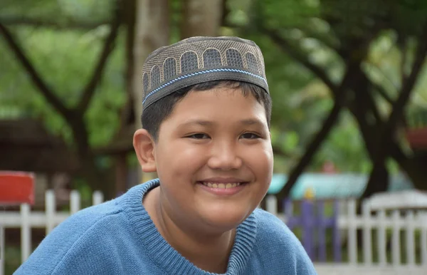 在学校公园里坐着的亚洲穆斯林或伊斯兰男孩的画像 开心地笑着 柔软而有选择性地集中注意力 — 图库照片