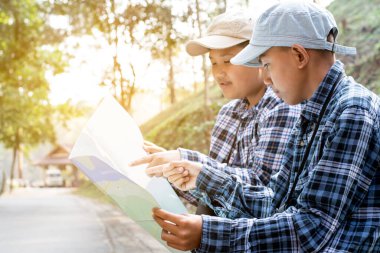 Asian boy held binoculars in hands and doing the bird watching, fish watching and forest observing in local national park, asian children summer vacation concept.