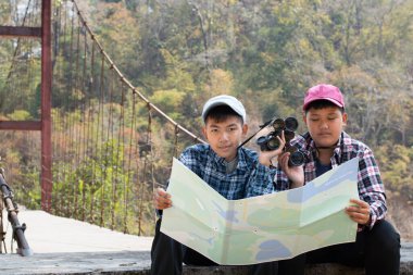 Asian boy held binoculars in hands and doing the bird watching, fish watching and forest observing in local national park, asian children summer vacation concept.