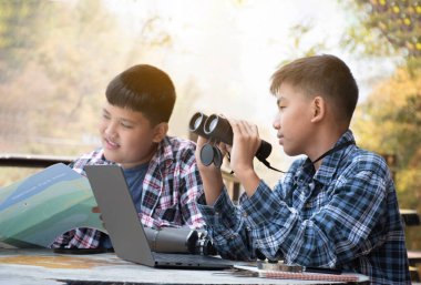Asian boy held binoculars in hands and doing the bird watching, fish watching and forest observing in local national park, asian children summer vacation concept.