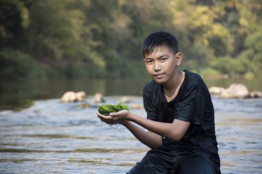 Asian schoolboy holding freshwater algae from diving into the river and pulling it up to study the fertility of the river's nature and including to do freshwater algae in his environment project work.