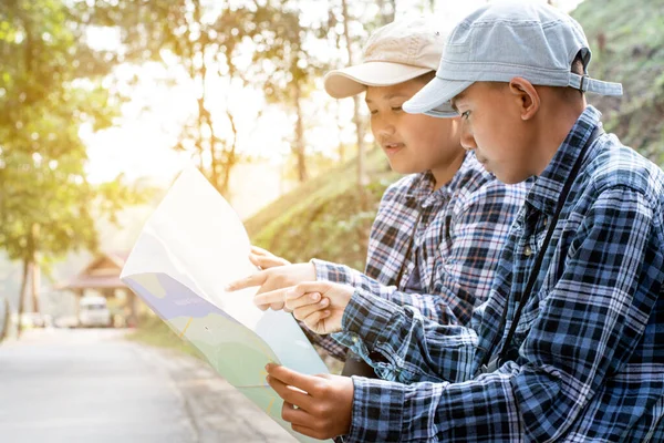 Asian boy held binoculars in hands and doing the bird watching, fish watching and forest observing in local national park, asian children summer vacation concept.