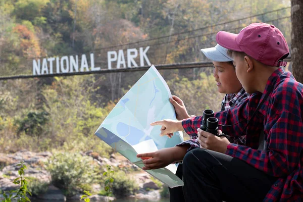 Asian boy held binoculars in hands and doing the bird watching, fish watching and forest observing in local national park, asian children summer vacation concept.