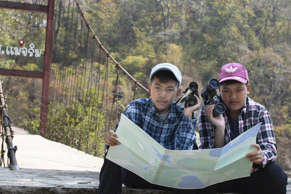 Asian boy held binoculars in hands and doing the bird watching, fish watching and forest observing in local national park, asian children summer vacation concept.