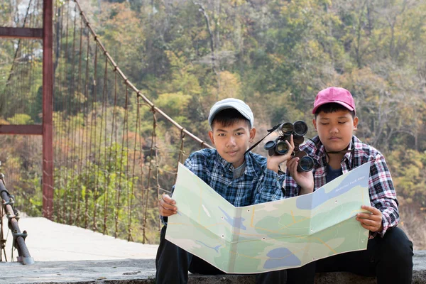 Asian boy held binoculars in hands and doing the bird watching, fish watching and forest observing in local national park, asian children summer vacation concept.