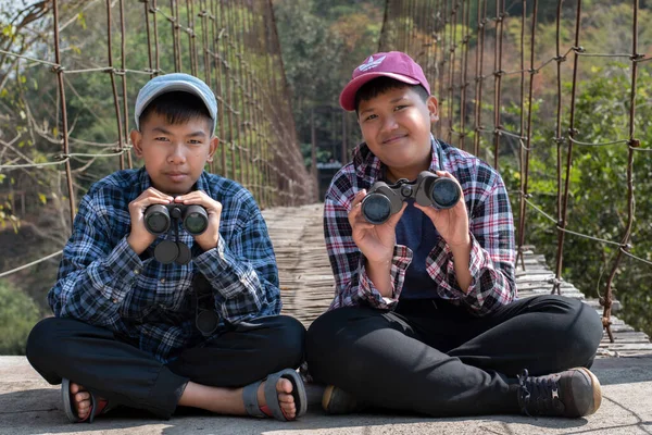 Asian boy held binoculars in hands and doing the bird watching, fish watching and forest observing in local national park, asian children summer vacation concept.