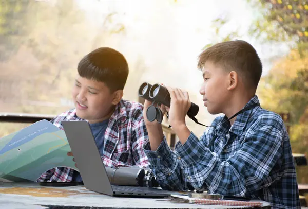 Asian boy held binoculars in hands and doing the bird watching, fish watching and forest observing in local national park, asian children summer vacation concept.