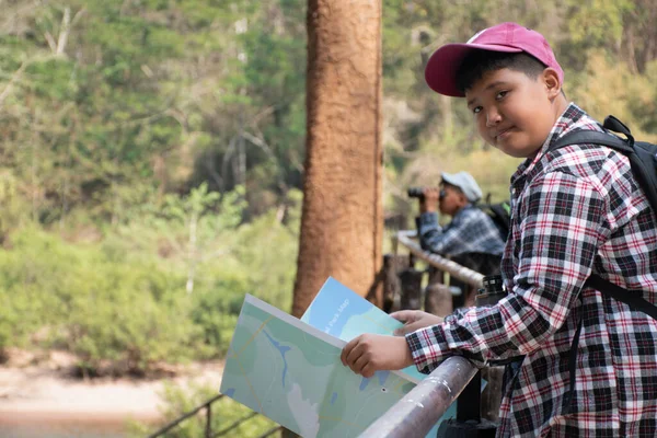 Asian boy held binoculars in hands and doing the bird watching, fish watching and forest observing in local national park, asian children summer vacation concept.