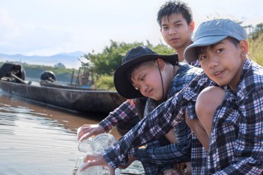 Asyalı çocuklar ellerinde büyüteç ve şeffaf plastik tüplerle, köylerinin etrafındaki nehirlerin verimliliğini ve çevresel sorunları incelemek için yerel nehirden gelen su deneylerine gidiyorlar..