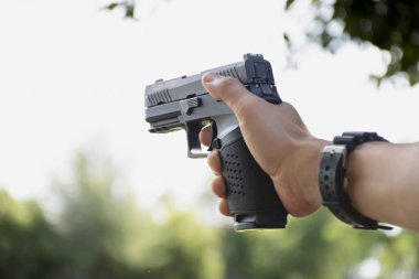 9 mm 'lik izole bir tabanca. Kesme yolları olan bir nişancının sağ elinde duruyor..