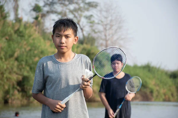 Азиатские Мальчики Держат Шаттл Бадминтона Ракетку Стоя Играя Берегу Реки — стоковое фото