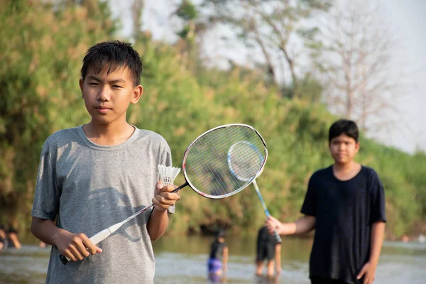 Азиатские Мальчики Держат Шаттл Бадминтона Ракетку Стоя Играя Берегу Реки — стоковое фото