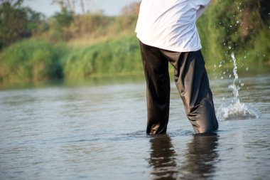 Sıradan giyinen Asyalı çocuk boş zamanlarını dalarak, yüzerek, taş atarak ve yerel nehirde mutlu bir şekilde balık tutarak, hobi, mutluluk ve yaz aktiviteleri yaparak geçiriyor.