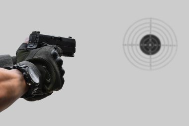 Atış poligonunun önünde 9 mm 'lik tabanca tutan silahlı bir adam..