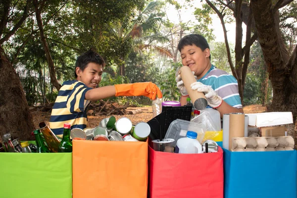 Asian boys in caucasian are separating garbages at the community\'s park, soft and selective focus, environment care, community service and summer vacation activities of teenagers concept.