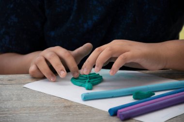 Otistik bir çocuk, ebeveynler tarafından normal çocuklardan daha yavaş beyin gelişimine sahip olan oğullarında çeşitli yönler geliştirmek için evde hazırlanmış farklı renkli plastikler üretiyor..